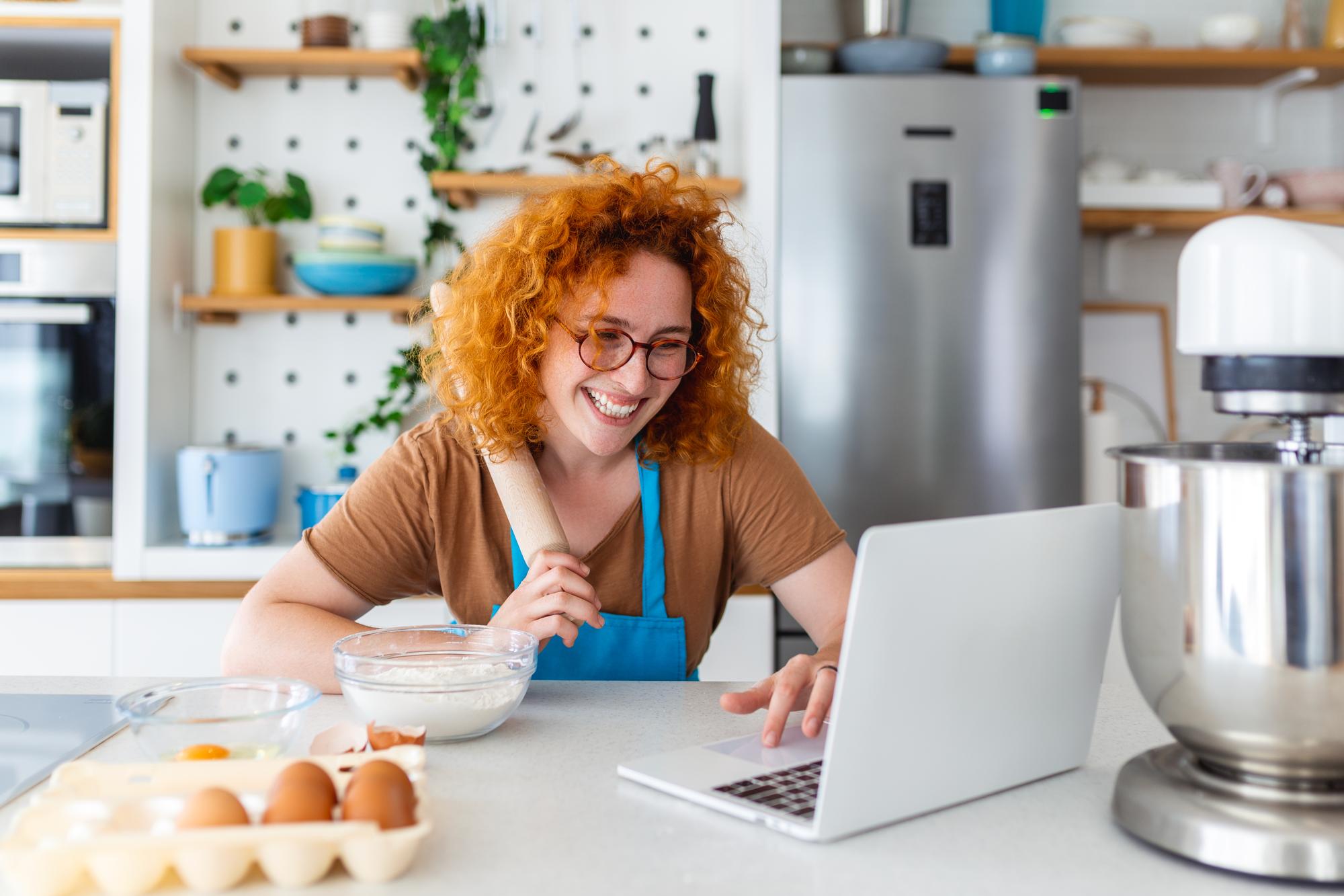 Student cooking along on laptop in small kitchen